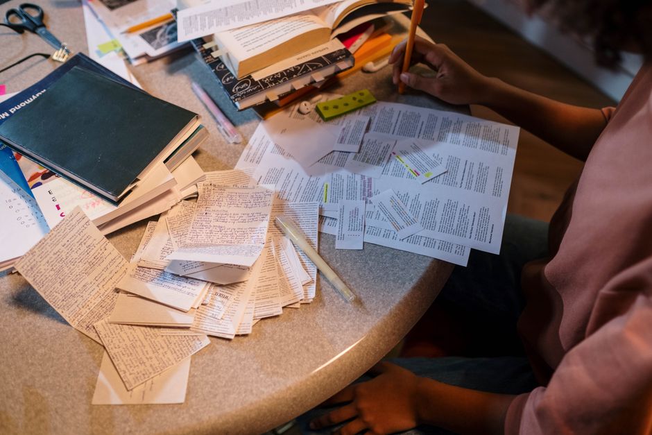 A student organizes notes and books in preparation for an exam, focusing on study material