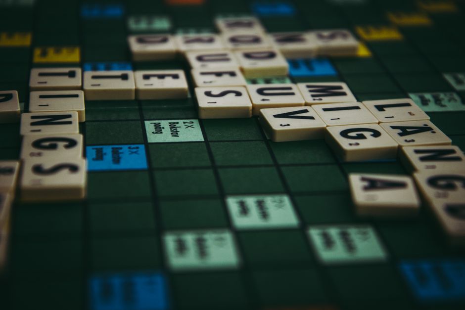 Close-up of a Scrabble board with words formed using tiles, showcasing strategic gameplay.