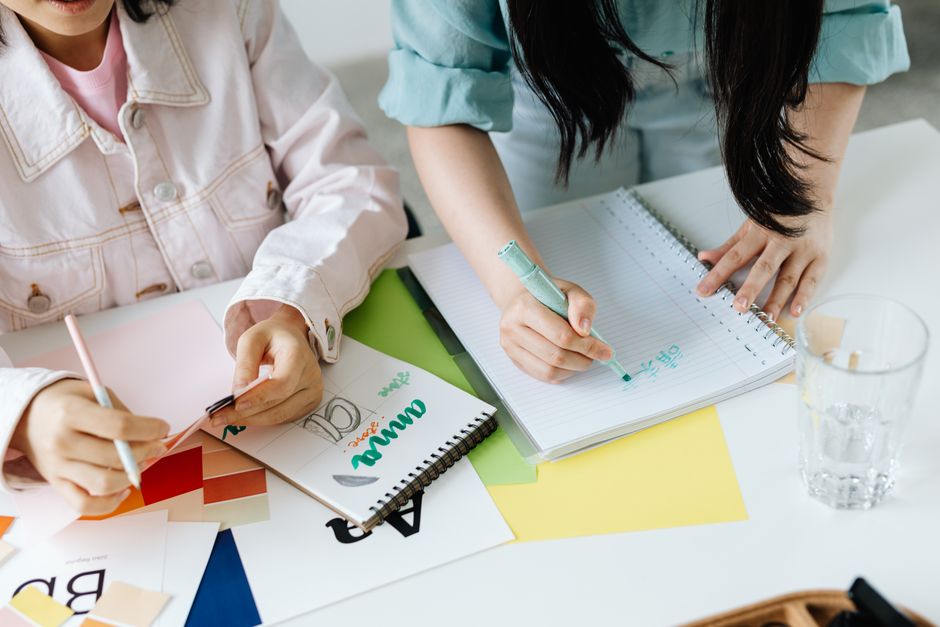 Two women collaborating on design ideas at a creative workspace with colorful materials.