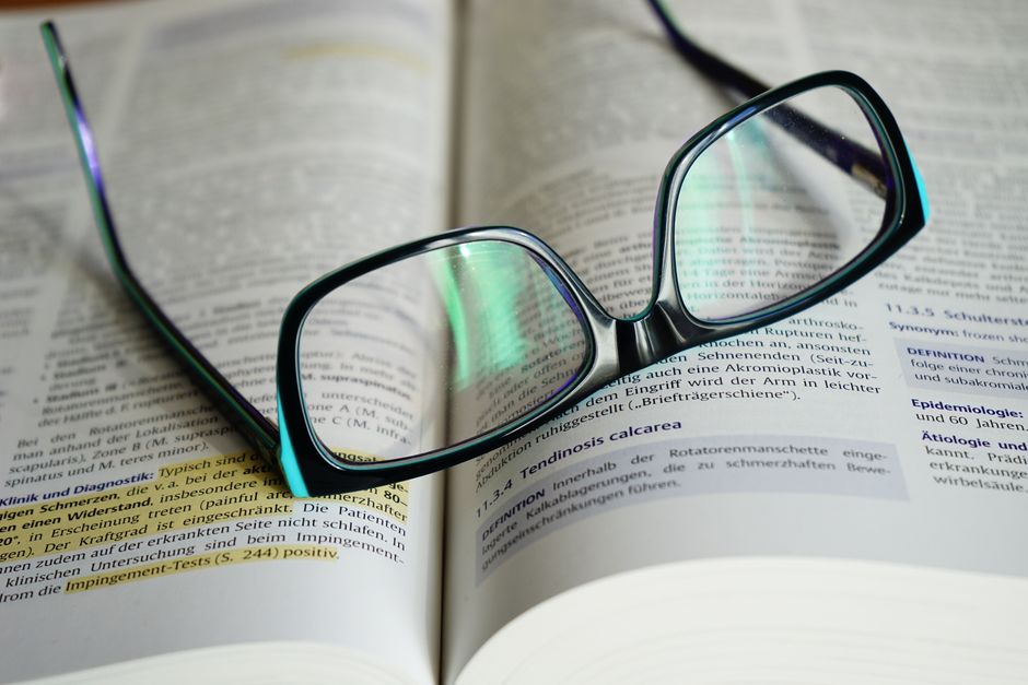 Reading glasses resting on an open book, symbolizing knowledge and learning.