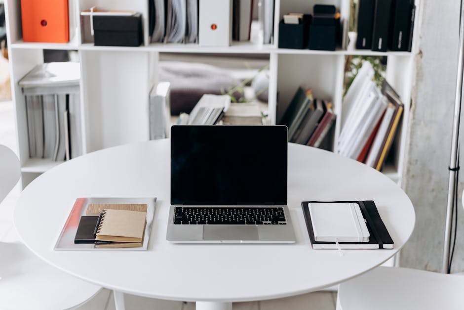 A sleek office setup featuring a laptop, notebooks, and stylish furniture, ideal for productivity.
