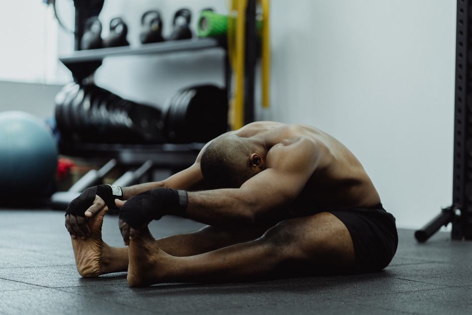Man doing seated stretch in gym, emphasizing fitness and flexibility training.