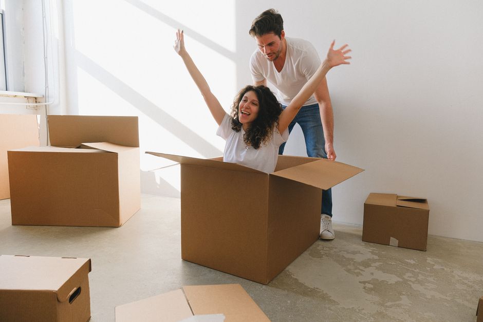 Happy couple enjoying a playful moment with cardboard boxes while moving into a new home.
