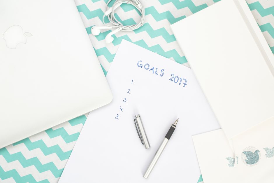 Photo of a workspace featuring a notepad labeled Goals 2017, pen, and laptop for planning.