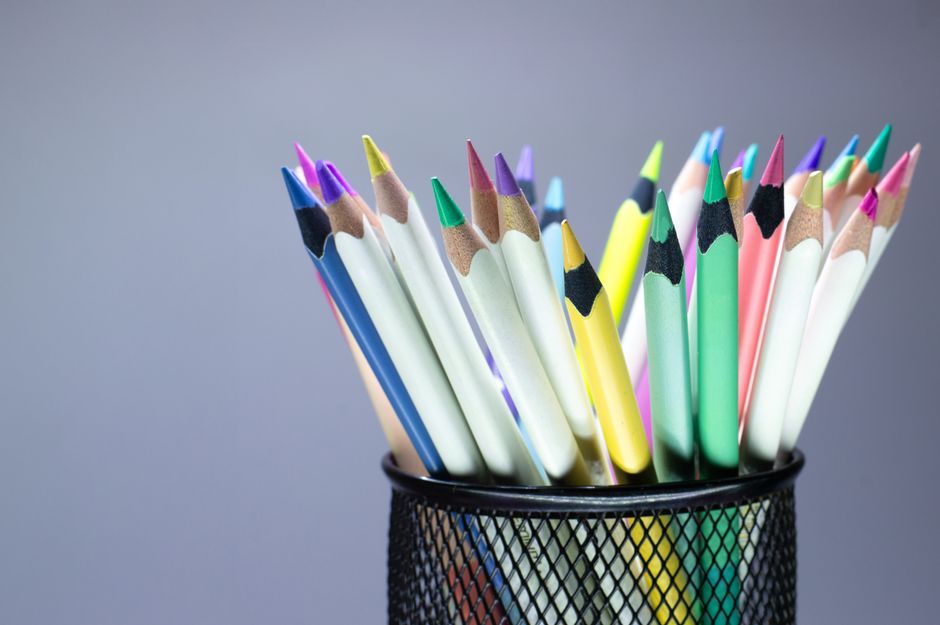 Close-up of colorful pencils in a mesh holder, perfect for art and creativity.