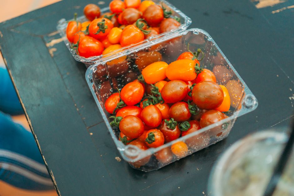 Two plastic containers filled with vibrant cherry tomatoes on a rustic wooden table.