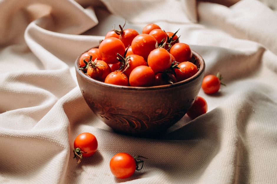 A rustic bowl filled with fresh cherry tomatoes on a cloth background. Perfect for food lovers.