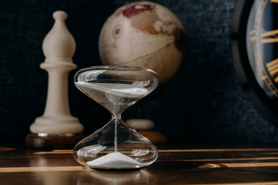 A vintage hourglass with a globe and clock, symbolizing time and travel.