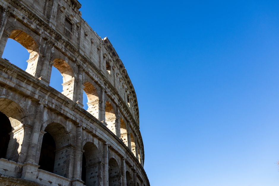 Stunning perspective of the Colosseum in Rome with a bright clear blue sky backdrop.