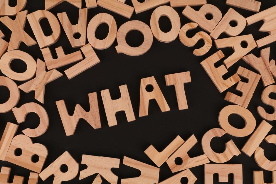 Artistic arrangement of wooden letters spelling 'WHAT' on a black background, offering creative inspiration.