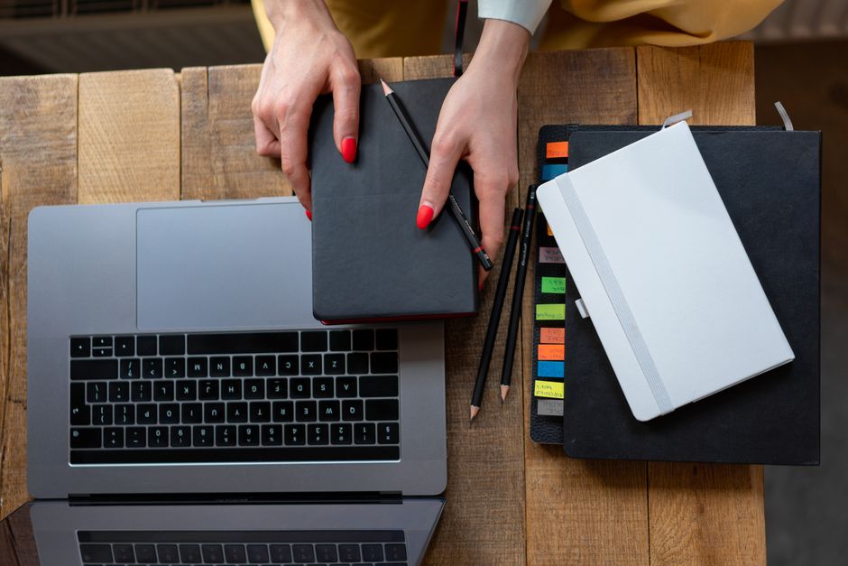 Top-down view of a desk with laptop, planner, and notebooks. Perfect for business and prod