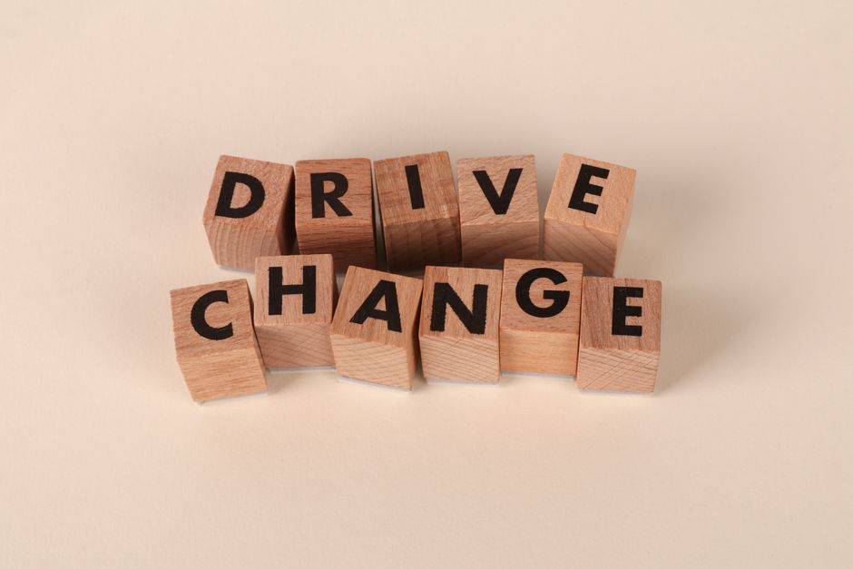 Wooden blocks spelling 'Drive Change' on a neutral background, symbolizing motivation and 